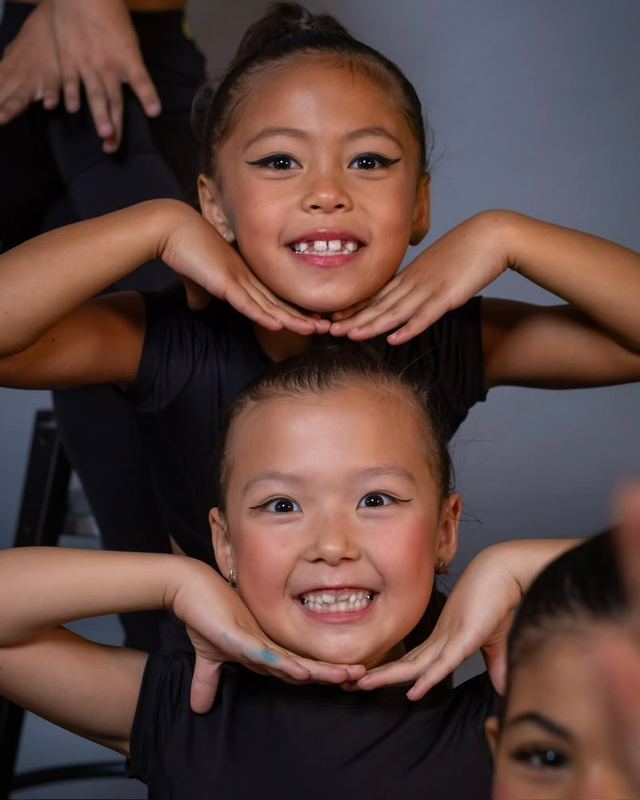 Two young gymnasts smiling at the camera during a session