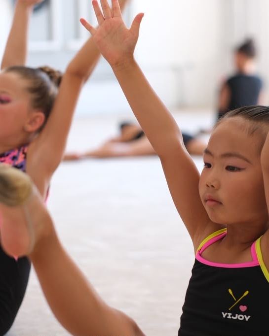 Young gymnasts reaching overhead during a warm-up