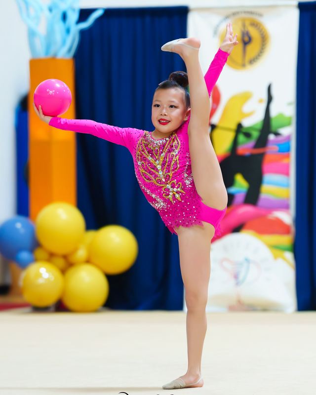 A gymnast balancing on one leg with a ball during a competition routine