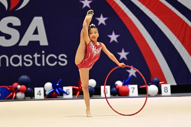 A gymnast holding an arabesque on the competition carpet