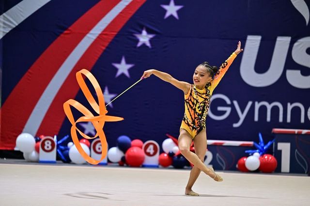 A gymnast reaching through a hoop during a floor routine