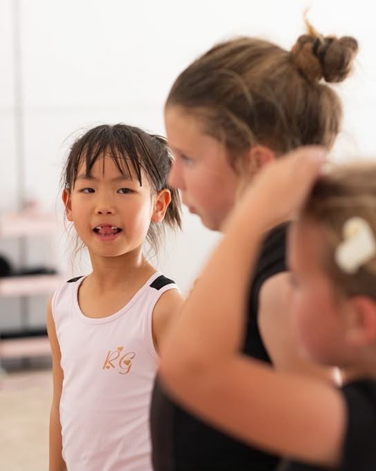 Two young gymnasts side by side during a class