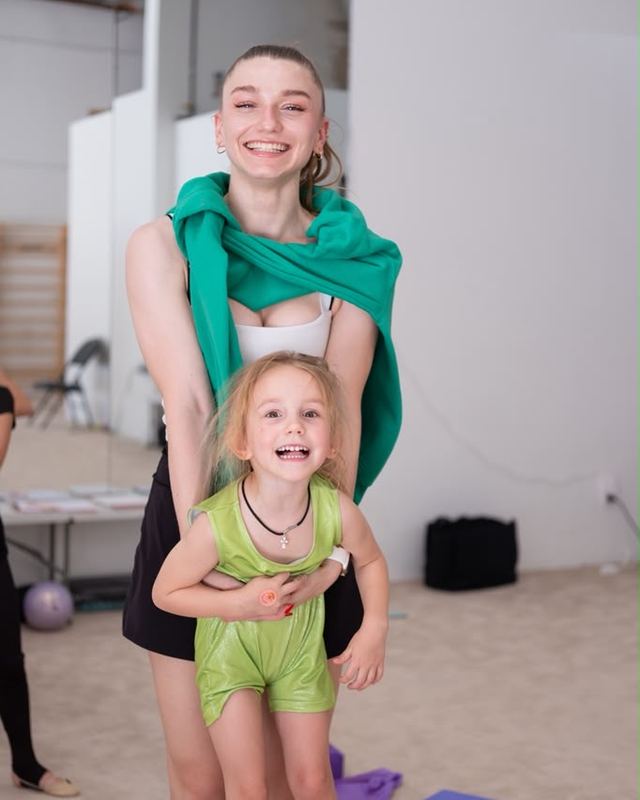 A coach and one of the youngest gymnasts laughing together