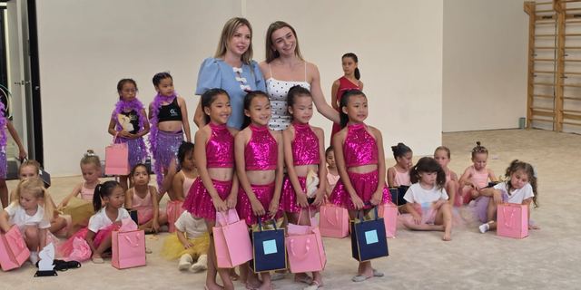 A performance group in pink sequins standing with their coaches
