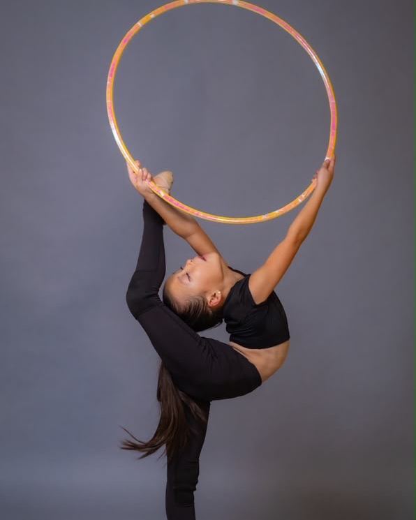 A gymnast lifting a hoop overhead